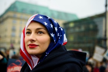 A woman wears a US flag like a hijab during a protest of US Democrats Abroad in front of the Brandenburg Gate in Berlin on January 21, 2017, one day after the inauguration of the US President. / AFP PHOTO / dpa / Gregor Fischer / Germany OUT